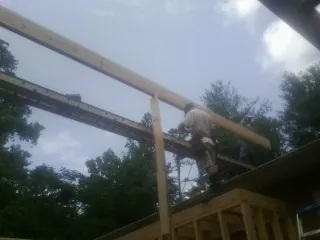 Carpenter setting a ridge beam over a new addition frame — Ice Dam Removal by Roofing Brothers in Avenel