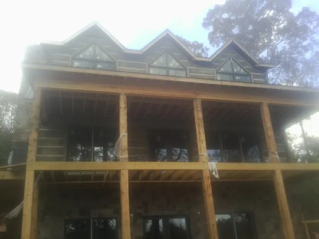 Dormers and porch framing on a large log home under construction — Roof Coating work by our crew in Avenel