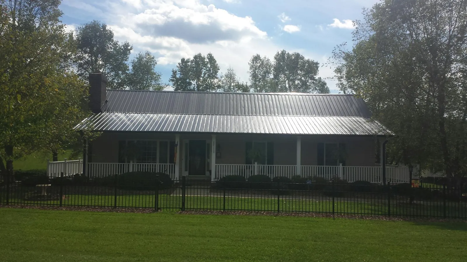 Gray metal roof on a brick ranch with a full width front porch — Gutter Guard Installation work by our crew in Avenel