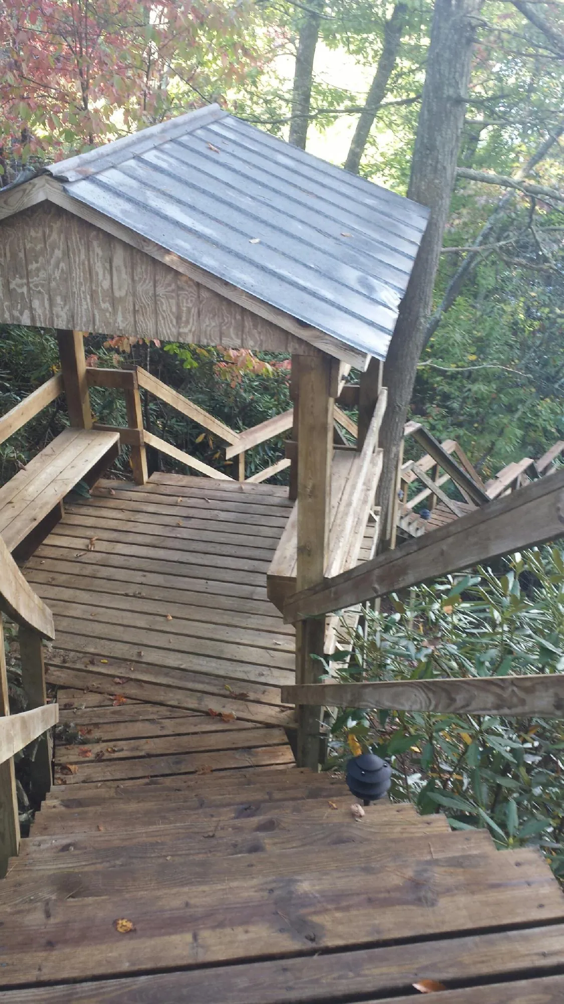 Metal roofed shelter over wooden steps on a wooded walkway — Skylight Repair & Installation work by our crew in Avenel
