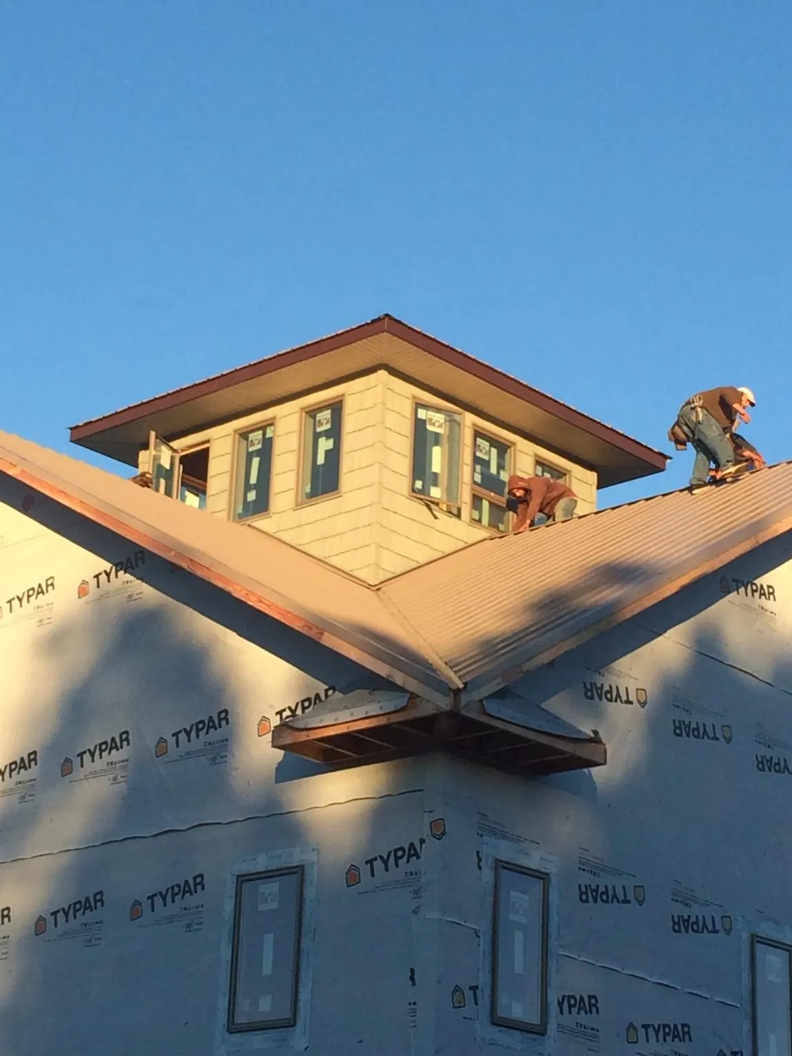 Roofers working around a rooftop cupola on a new metal roof at sunset — Roof Waterproofing in Avenel by Roofing Brothers